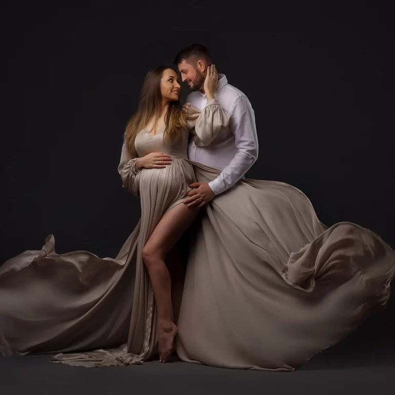 Taupe fabric billows; romantic couple’s portrait against dark backdrop.