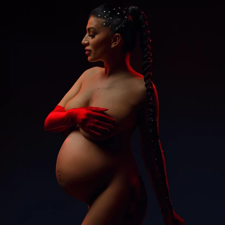 Dramatic lighting; pearl‑dotted braid and single red glove; bold profile.