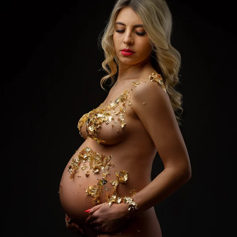 Gold leaf art across shoulders, chest, and belly; dark, elegant backdrop.