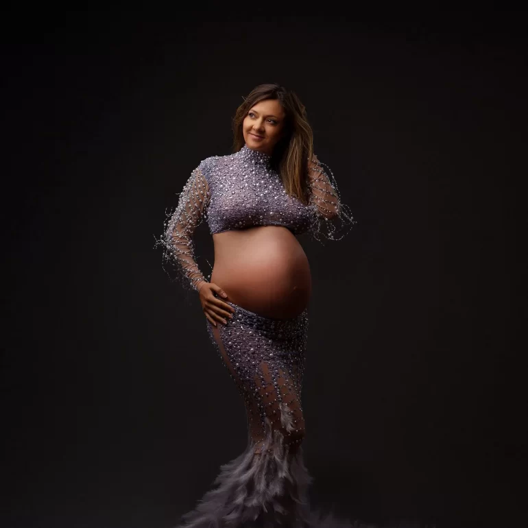 Lavender beaded gown with feathers; confident pose in dark studio.