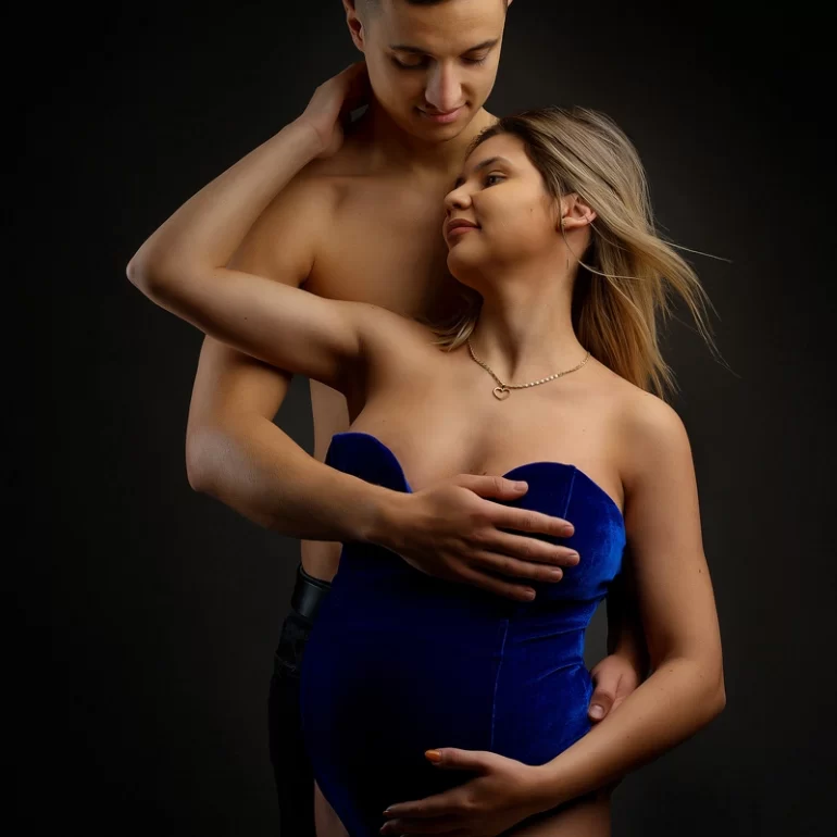 Blue velvet bodysuit; partner’s gentle embrace; warm anticipation.