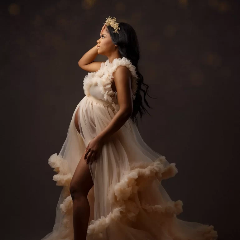 Profile in layered beige ruffles; delicate gold crown; warm bokeh.