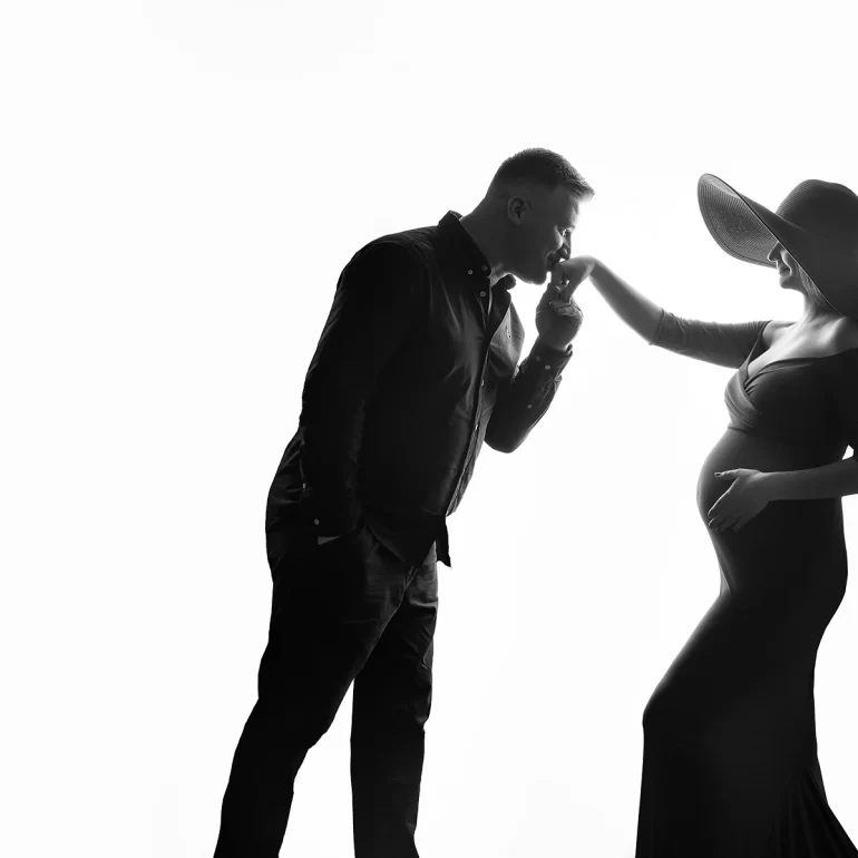 B&W couple; he kisses her hand; wide‑brim hat; refined elegance.