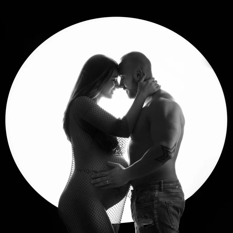 Black‑and‑white couple’s silhouette before bright circular backlight.