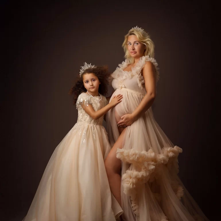 Mother and daughter in tulle with tiaras; tender bond.