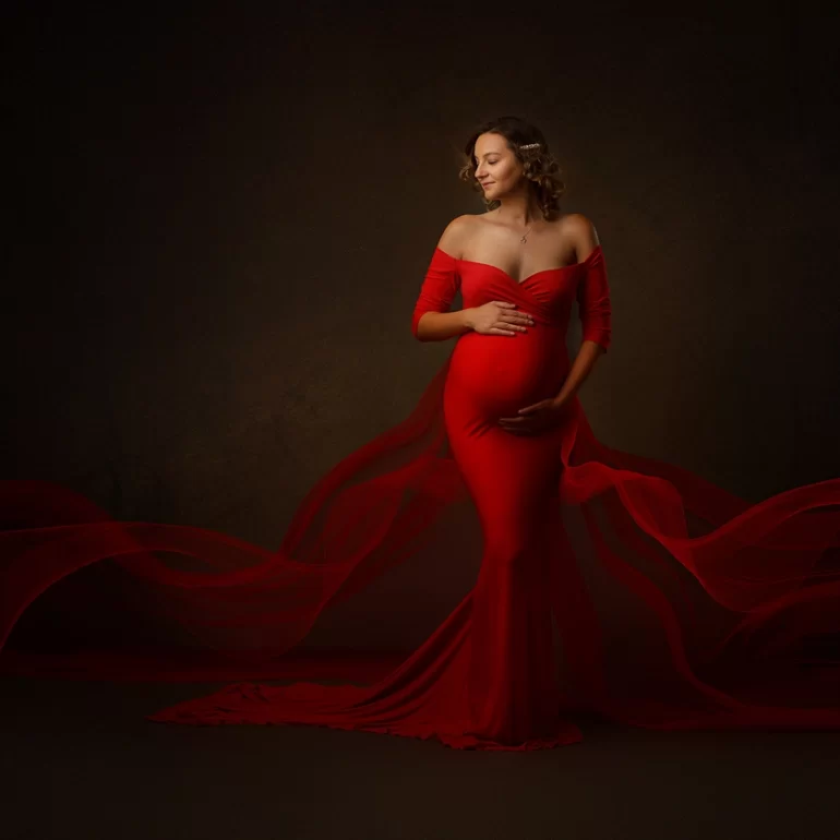 Vibrant red, form‑fitting gown with sheer extensions; serene smile.