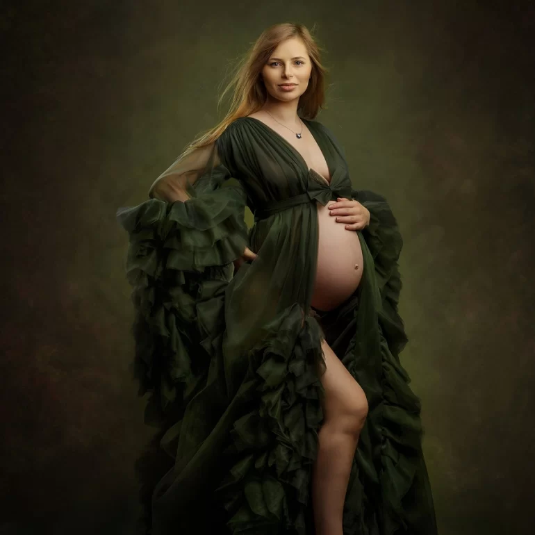 Flowing dark‑green gown, barefoot; gentle hand on bump, serene studio.