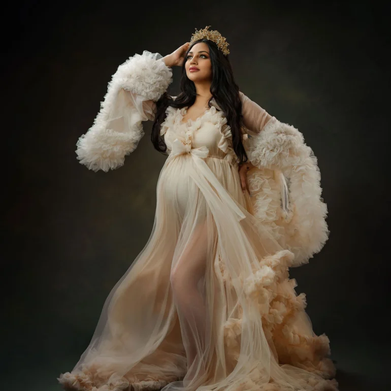 Sheer cream gown and golden crown; softly lit, enchanting pose.