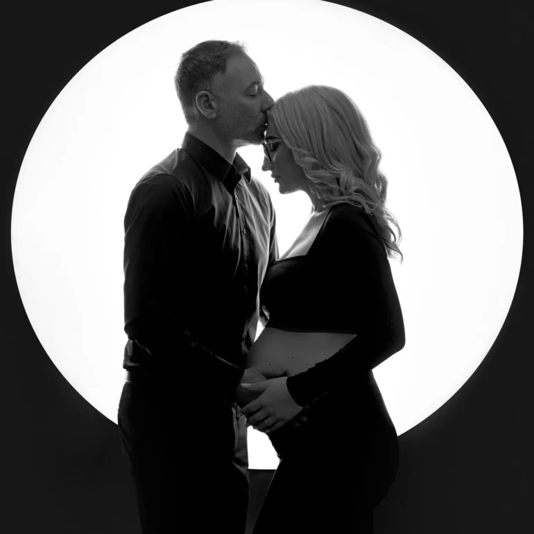 B&W couple with forehead kiss; dramatic circular backlight.