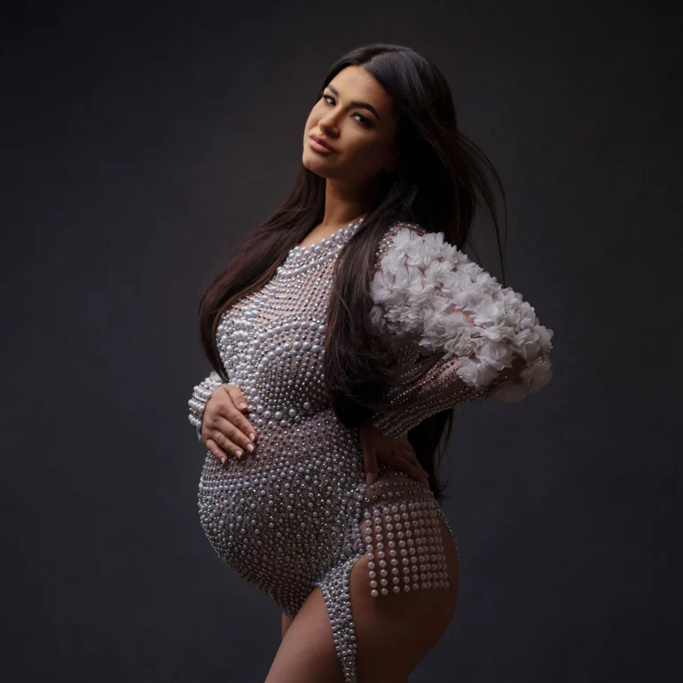 Pearl‑embellished bodysuit with floral sleeves; refined stance.